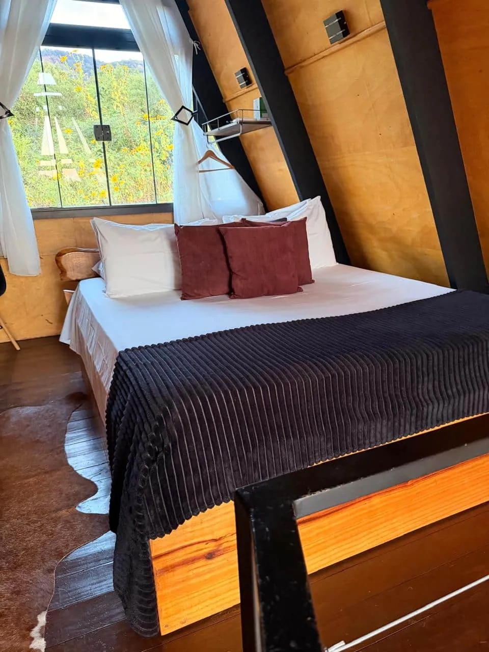 Cama de casal no mezanino, junto à janela com vista para o verde