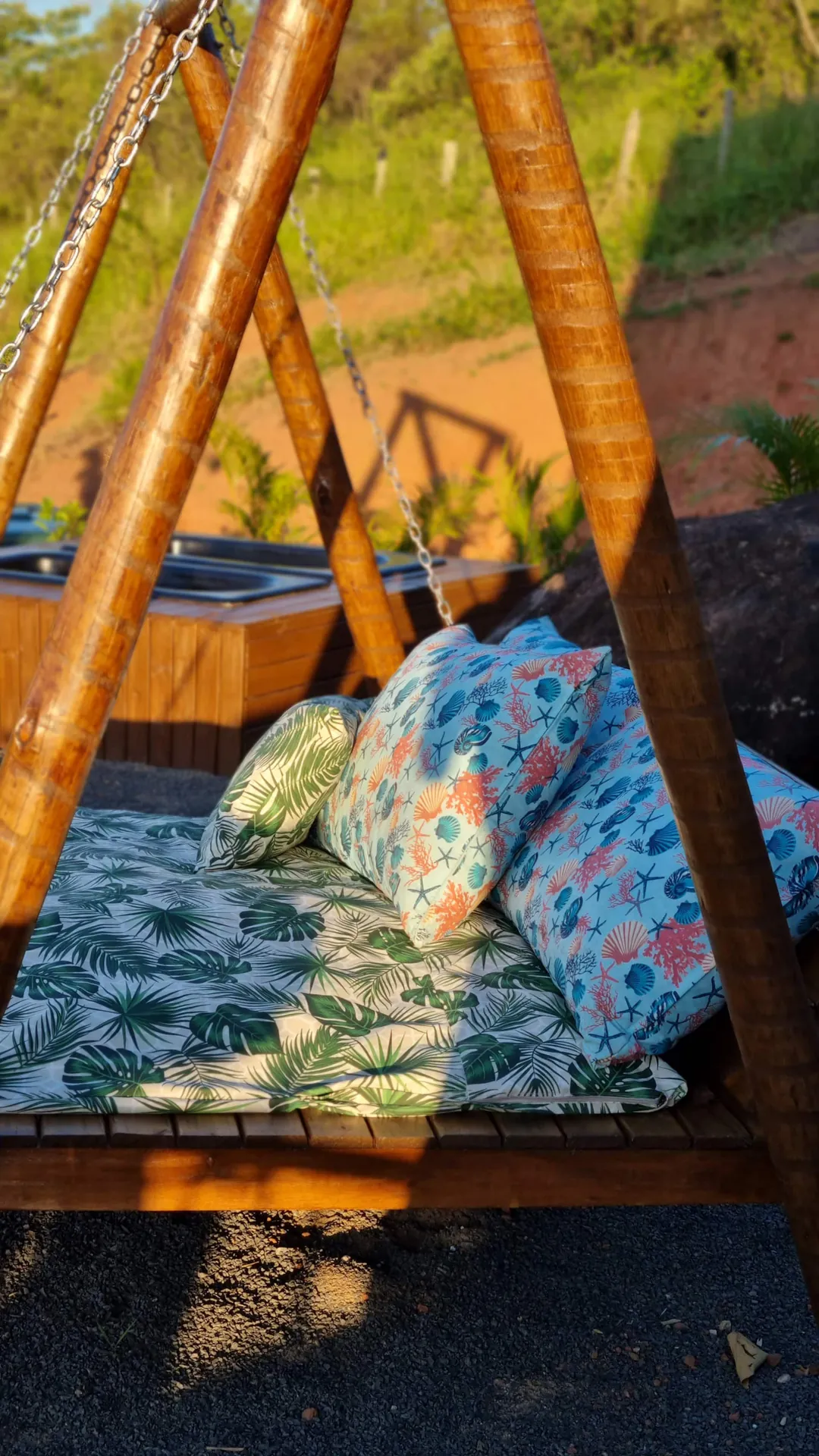 Cama-balanço de madeira com almofadas estampadas