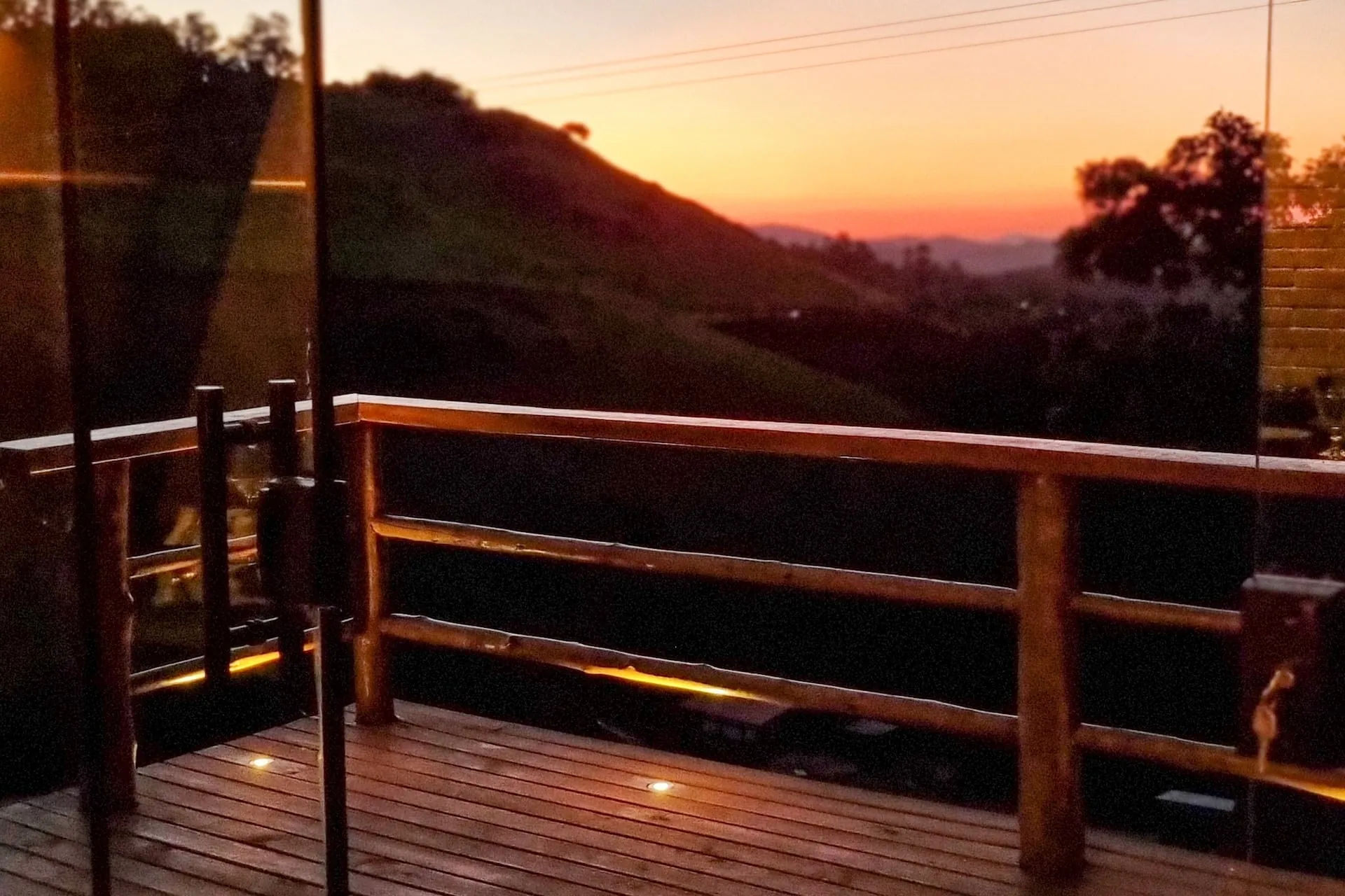 Deck de madeira com o pôr do sol atrás das montanhas